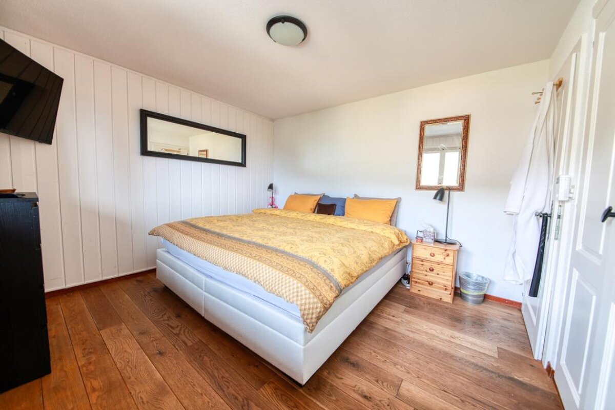 A bedroom with a large bed and a mirror