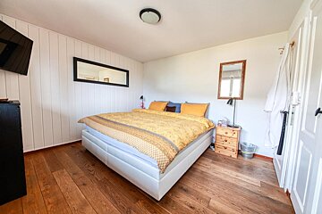 A bedroom with a large bed and a mirror