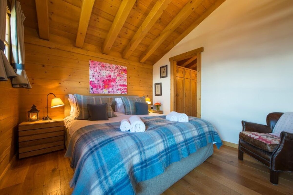 A bedroom with a painting on the wall above the bed
