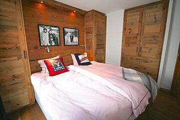 A bed with a pink comforter and a pillow that says california on it