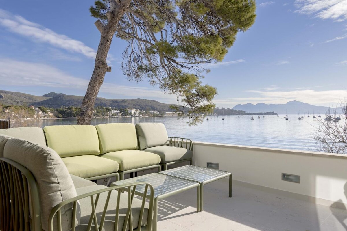 A balcony with a couch and a table overlooking a body of water