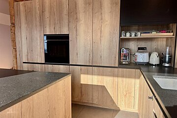 A kitchen with wooden cabinets and black counter tops