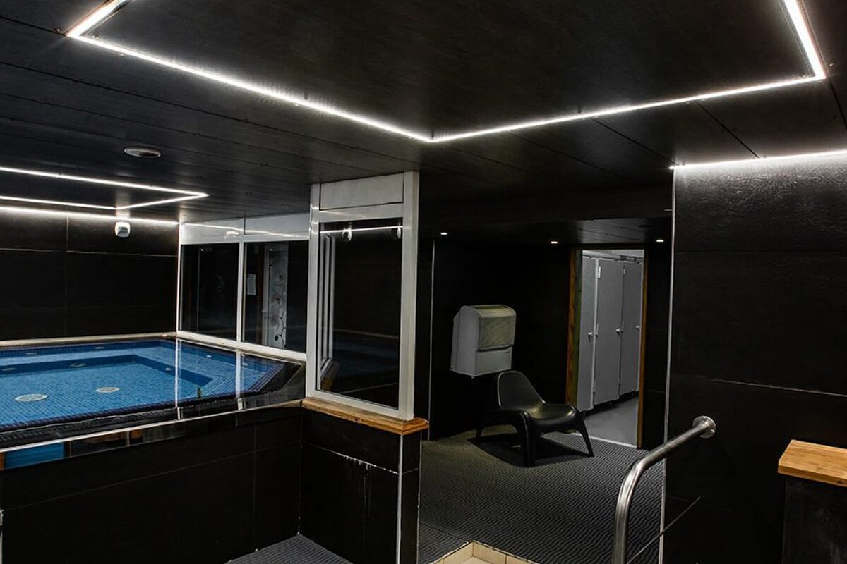 A swimming pool in a dark room with lights on the ceiling