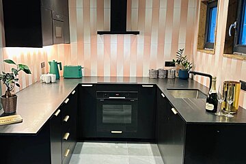 A kitchen with black cabinets and a bottle of champagne on the counter
