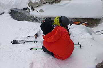 a man helping a skier out of a water hole