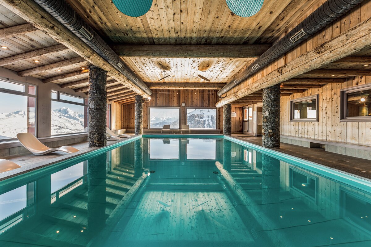 A large indoor swimming pool with a wooden ceiling