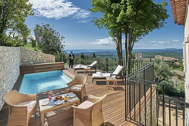 A man stands on a balcony overlooking a swimming pool