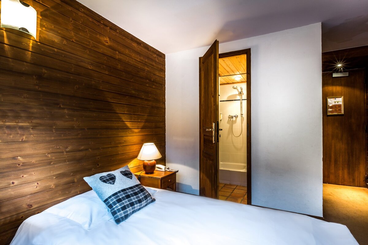 A bedroom with a wooden wall and a white bed