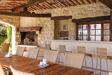 A table with wicker chairs and a fireplace in the background