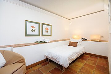 A bedroom with a single bed and two framed pictures on the wall