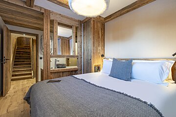 A bedroom with a bed and stairs leading to the bathroom