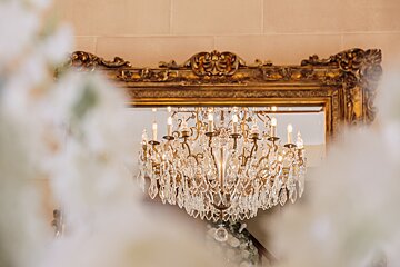 A large chandelier hangs in front of a mirror
