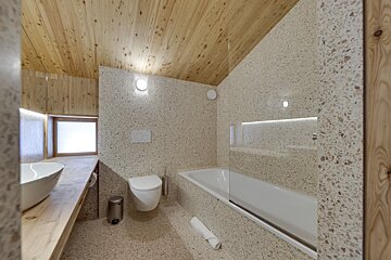 A bathroom with a toilet sink and bathtub with a wooden ceiling