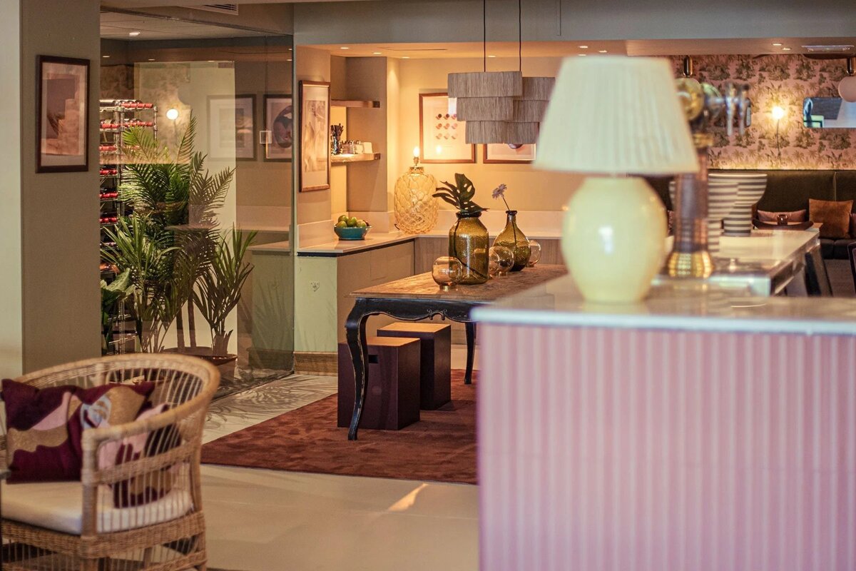 Modern, stylish interior with a cozy bar/dining area, warm lighting, plants, and decorative accents.