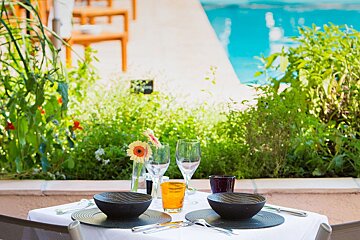 A table with bowls and glasses on it with a pool in the background