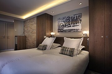 A hotel room with two beds and a painting on the wall