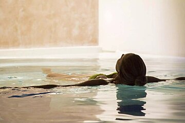 A woman is floating in a pool with her eyes closed