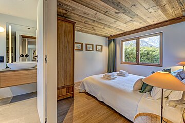 A bedroom with a white bed and a wooden ceiling