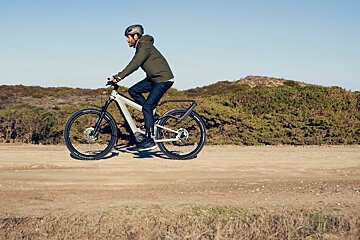 A man wearing a helmet is riding a bike on a dirt road
