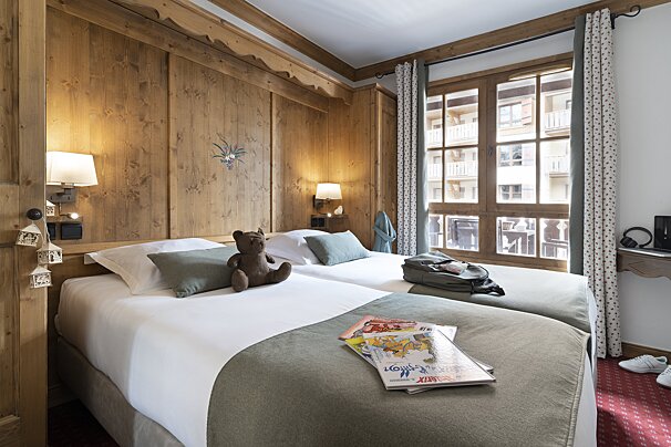 A hotel room with two beds and a teddy bear on the bed