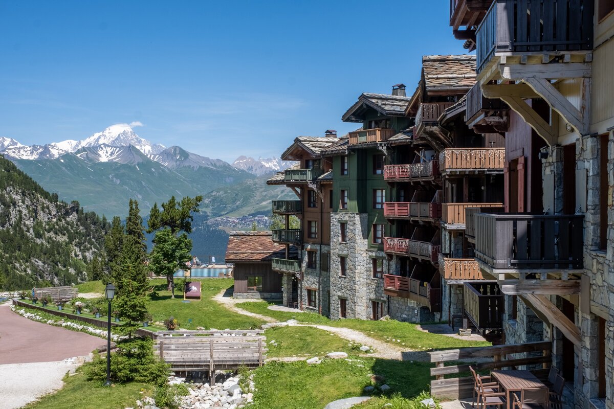 A row of buildings with balconies and mountains in the background