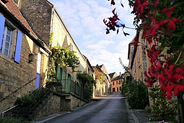 a street with flowers & coloured shutters in Domme