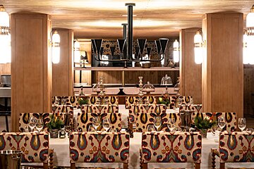 A dining room with tables and chairs and a chandelier hanging from the ceiling