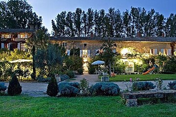 A large house with a playground in front of it is lit up at night