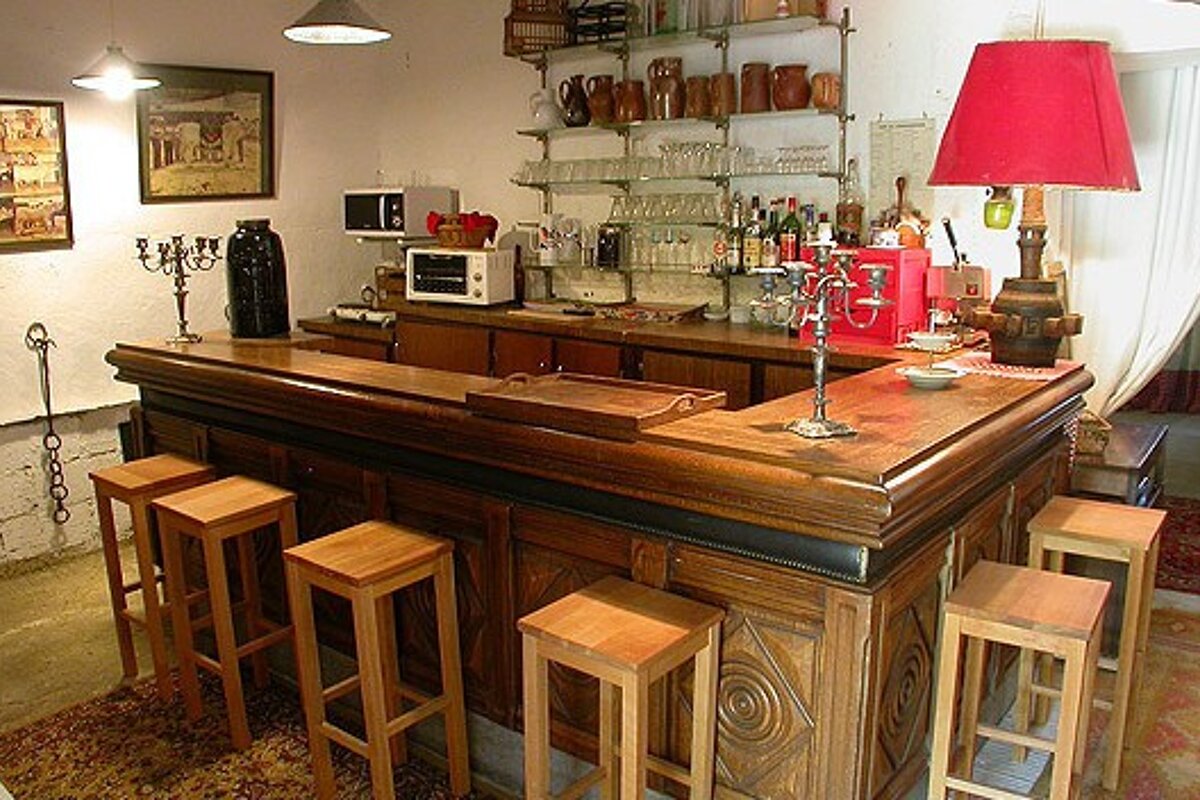 A large wooden bar with stools and a red lamp