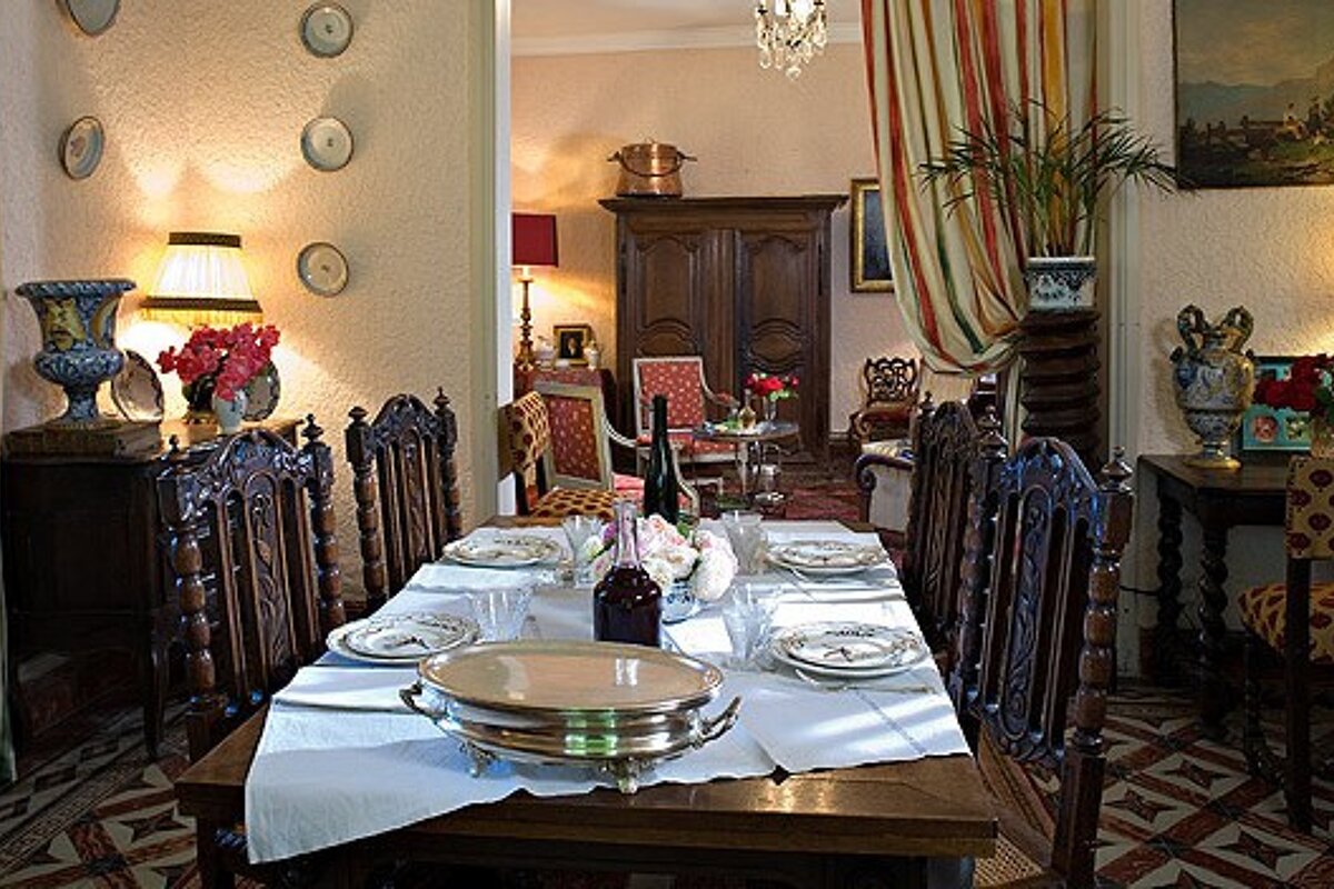 A dining room with a table and chairs and plates on it
