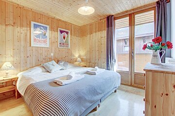 A bedroom with two posters on the wall one of which says morzine