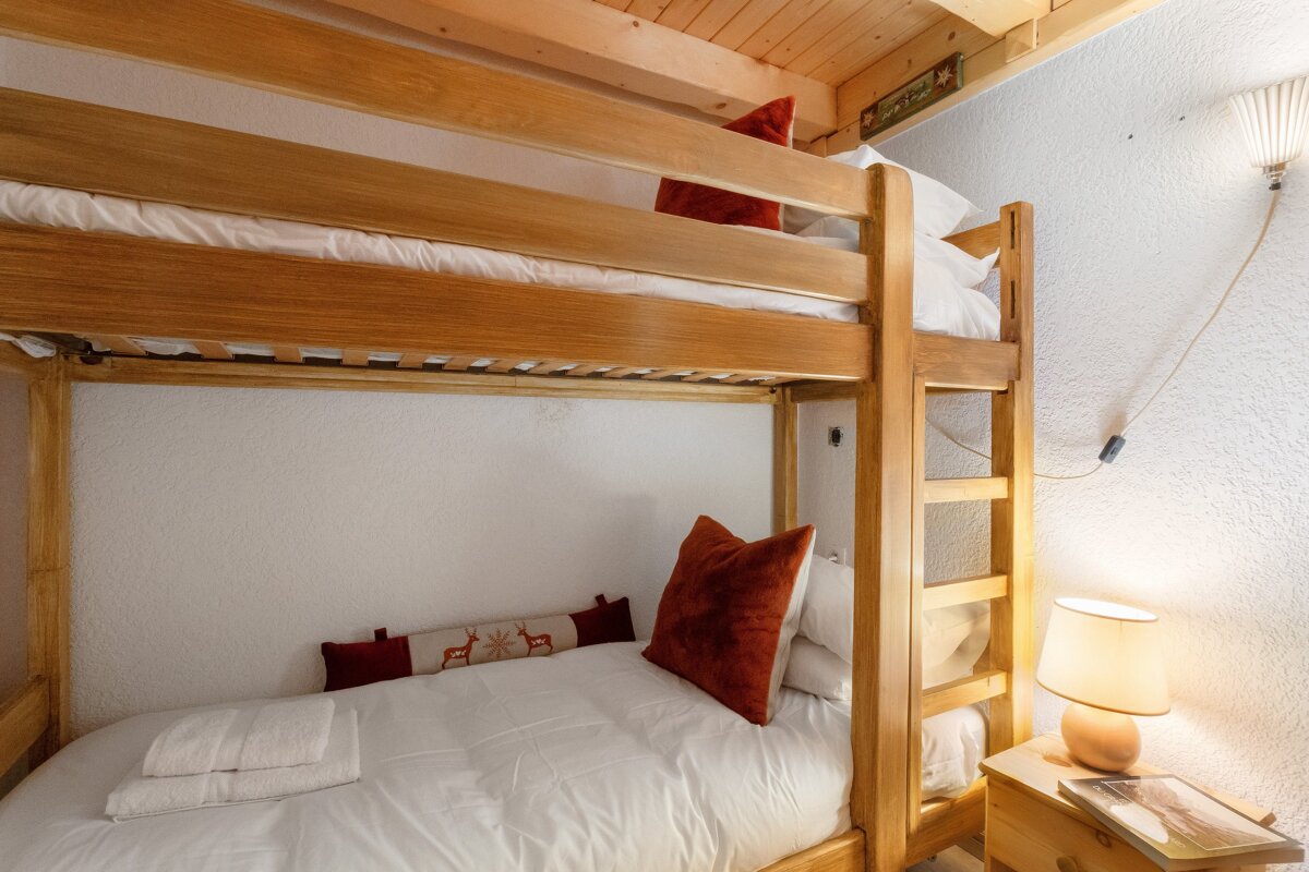 A bunk bed with red pillows and white sheets