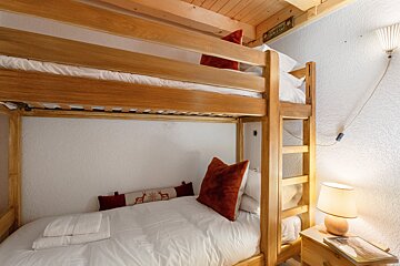 A bunk bed with red pillows and white sheets