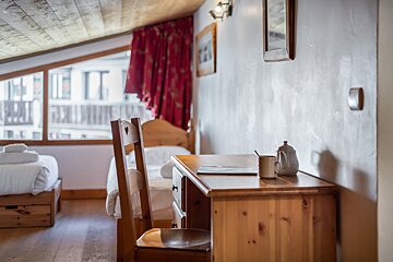 A bedroom with two beds and a desk with a cup on it