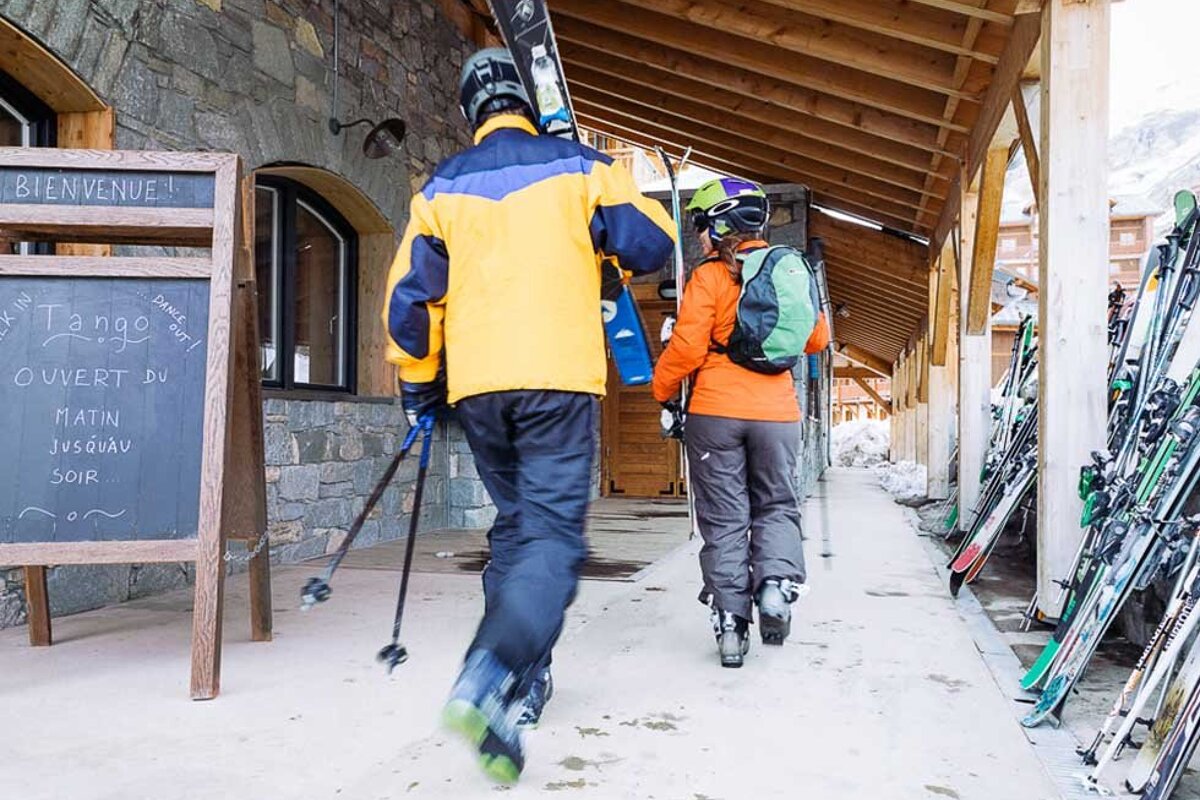 Two skiers are walking in front of a sign that says bienvenue