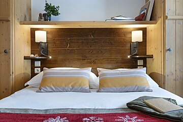 A bed with two pillows and a wooden headboard