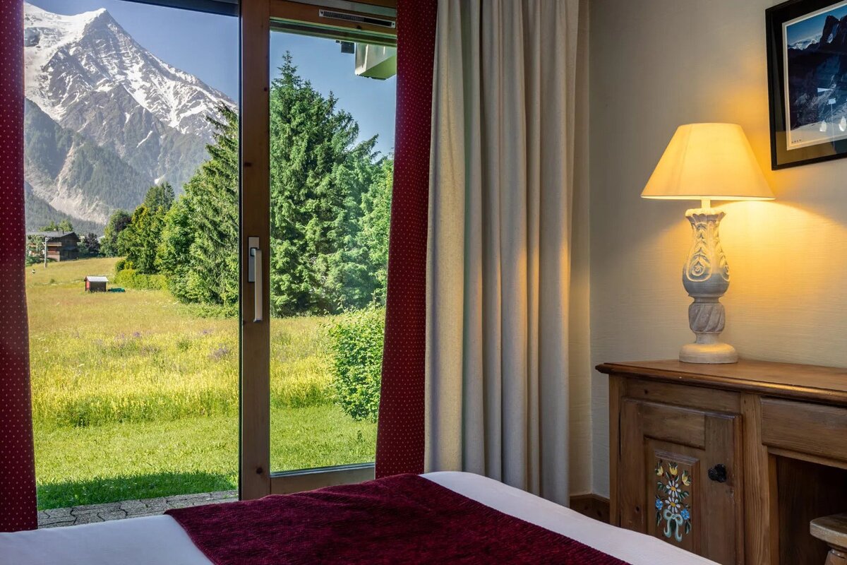 A bedroom with a lamp and a view of a mountain
