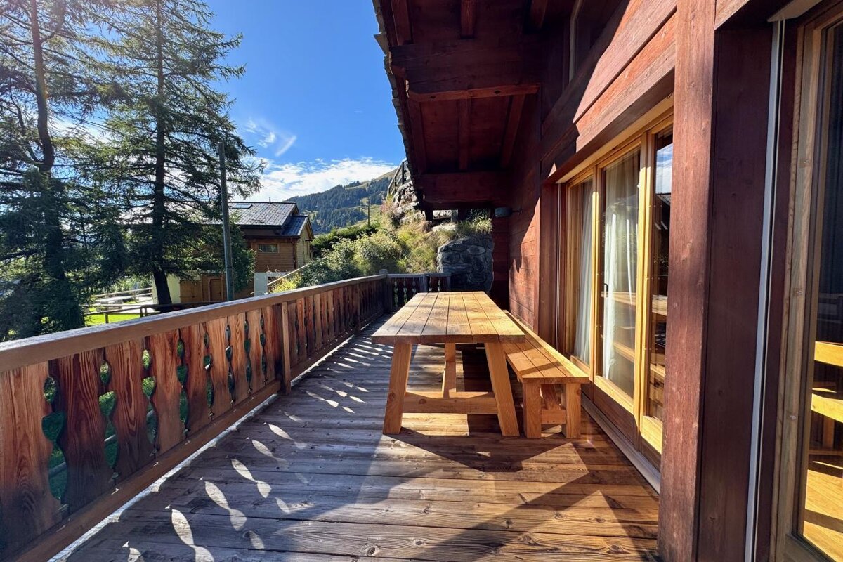 A wooden deck with a picnic table and benches