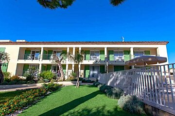 A large building with green shutters and a white umbrella in front of it