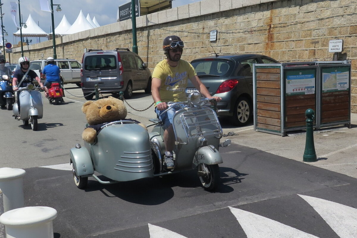 a man with a vespa & teddy in side car
