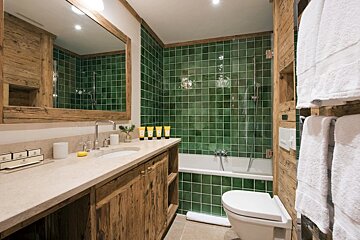 A bathroom with green tiles and a toilet