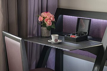 A table with a vase of flowers and a cup of coffee on it