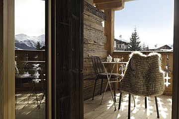 A fur vest sits on a chair on a balcony