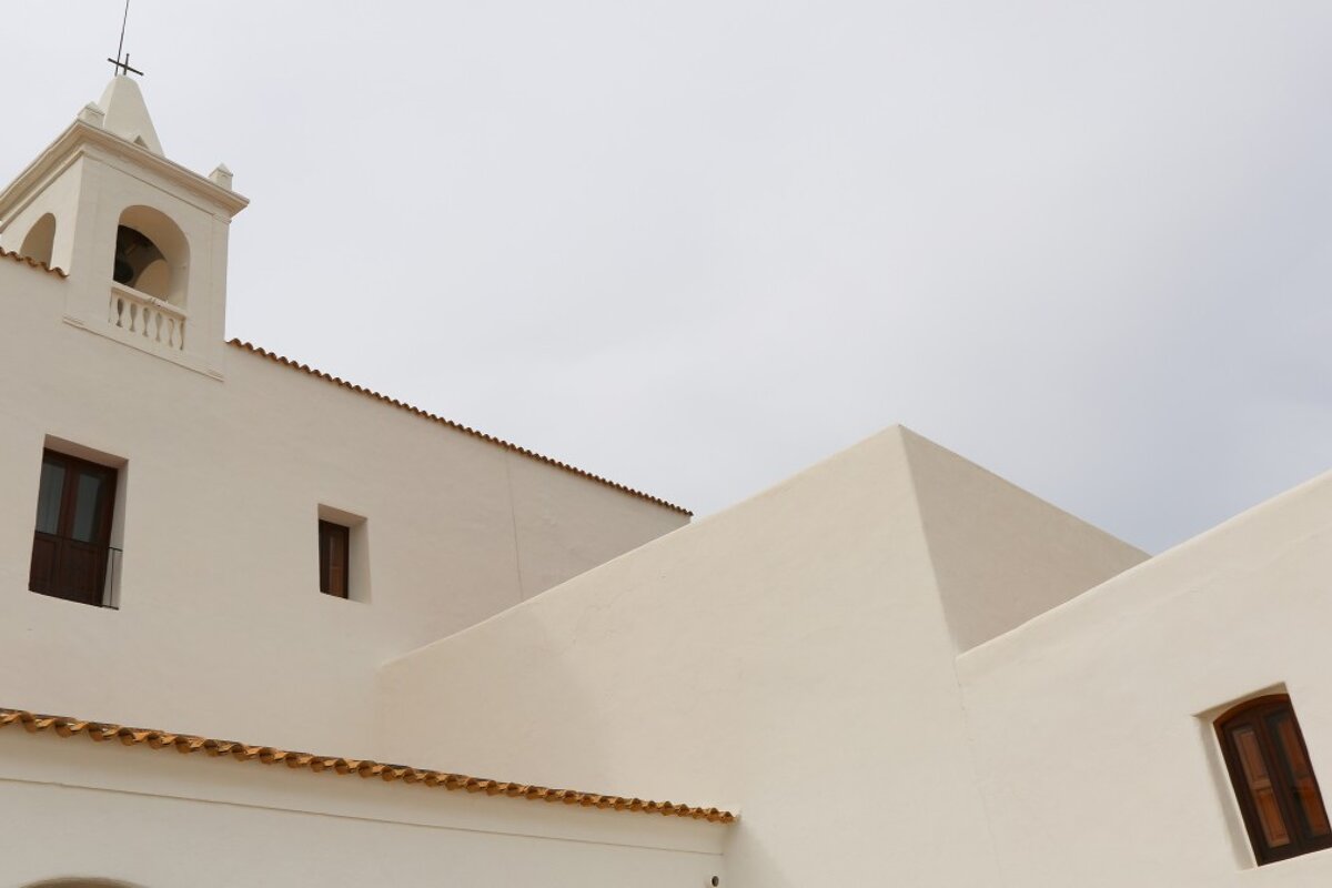 A white building with a bell tower and a cross on top