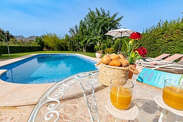 A basket of bread sits on a table next to a glass of orange juice