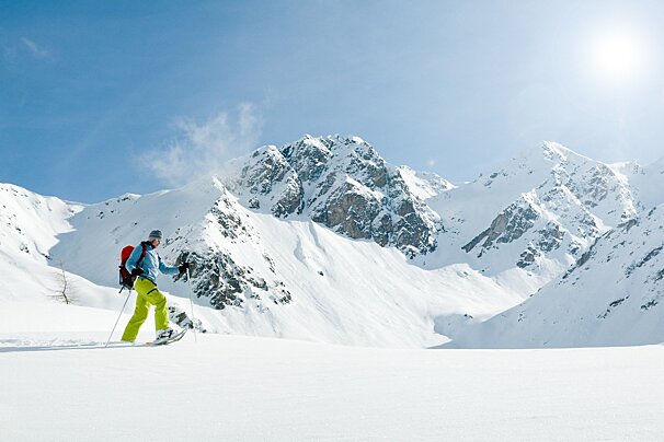 A person walking in the snow with mountains in the background