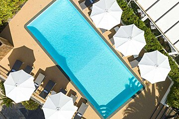 An aerial view of a large swimming pool surrounded by chairs and umbrellas