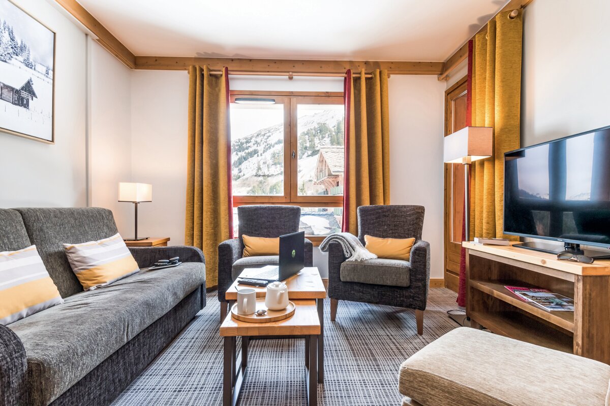 A living room with a couch two chairs and a flat screen tv