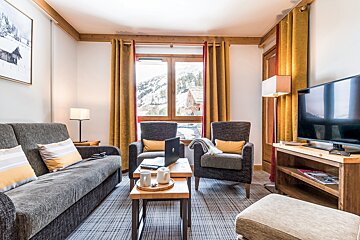 A living room with a couch two chairs and a flat screen tv