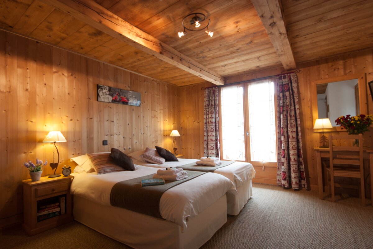 A bedroom with two beds and a painting on the wall